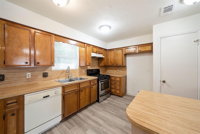 kitchen with dishwasher, stainless steel gas range oven, sink, decorative backsplash, and light hardwood / wood-style floors