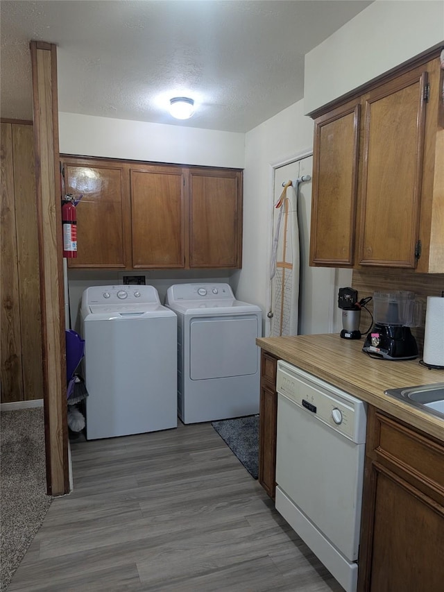 clothes washing area with light wood-type flooring, a textured ceiling, and independent washer and dryer