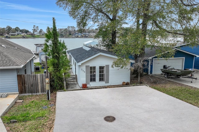 view of front of home with a garage, a water view, and an outbuilding