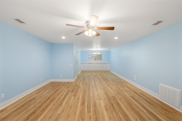 unfurnished room with ceiling fan with notable chandelier and light wood-type flooring