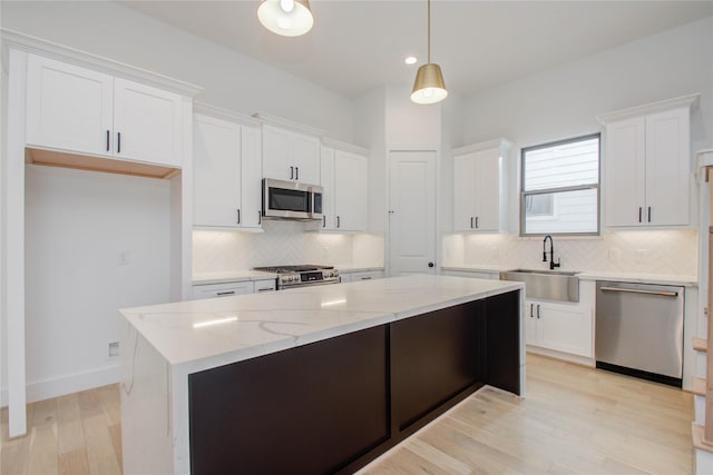 kitchen with a kitchen island, decorative light fixtures, sink, white cabinets, and stainless steel appliances