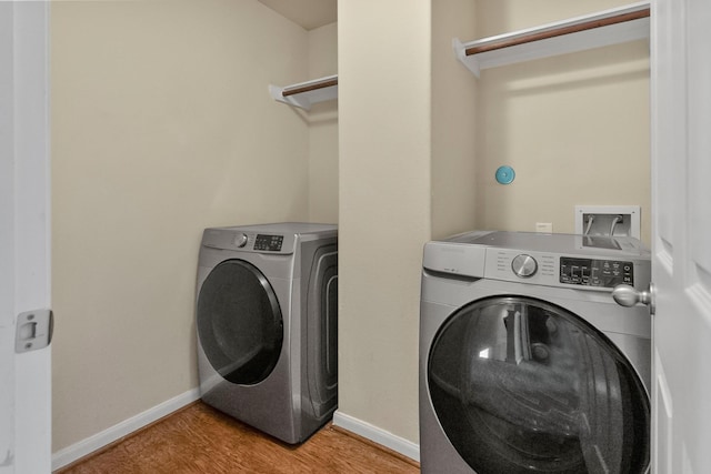 laundry room with washer and clothes dryer and light hardwood / wood-style floors