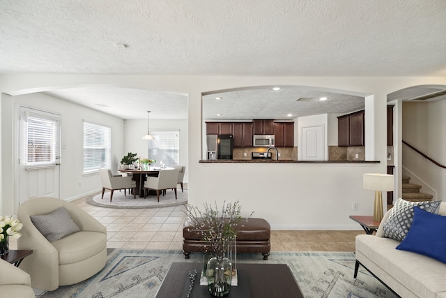 living room with sink, a textured ceiling, and light tile patterned flooring