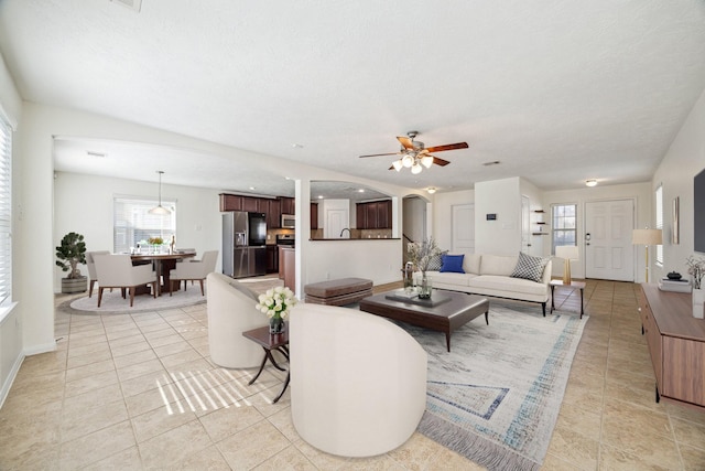 living room with ceiling fan, light tile patterned floors, and a textured ceiling