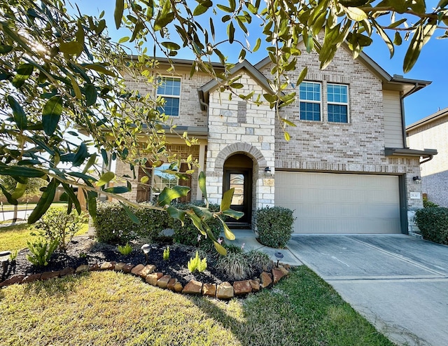 view of front of property featuring an attached garage, driveway, brick siding, and stone siding