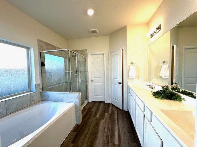 full bathroom with a garden tub, a sink, wood finished floors, double vanity, and a stall shower