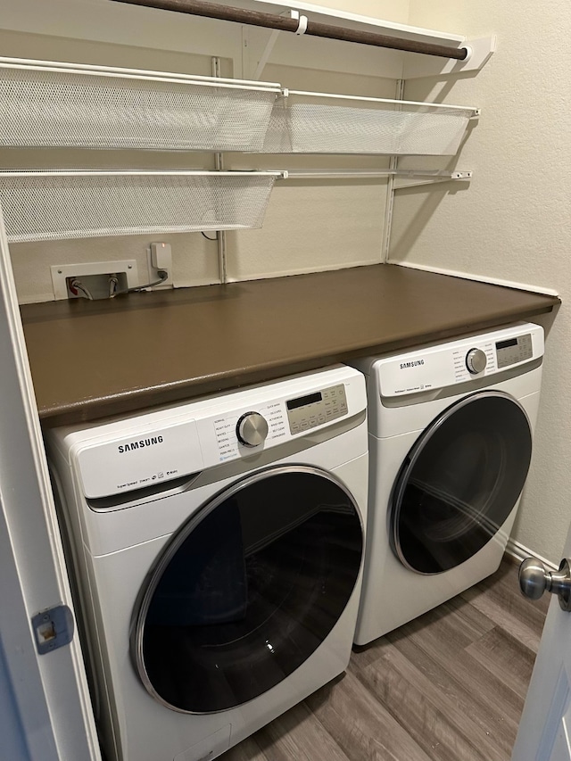 clothes washing area featuring laundry area, wood finished floors, and separate washer and dryer