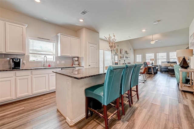 kitchen with a healthy amount of sunlight, visible vents, a sink, and a kitchen bar