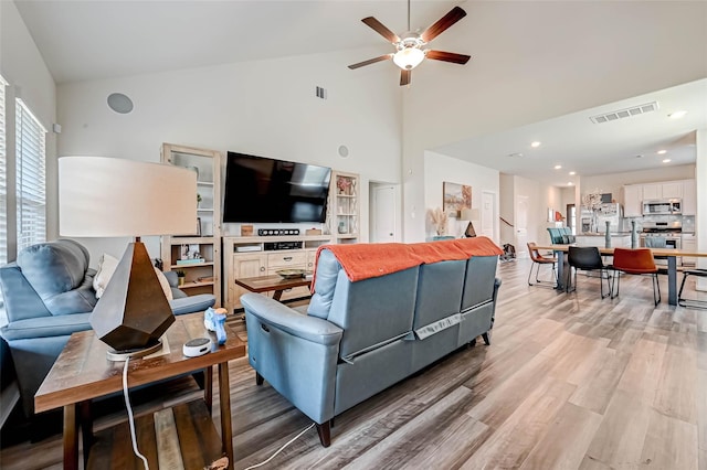 living room with ceiling fan, high vaulted ceiling, and light hardwood / wood-style floors