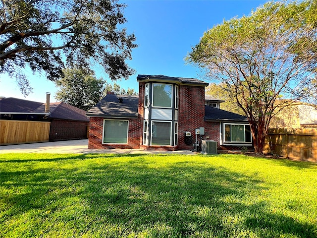 rear view of house with cooling unit and a lawn