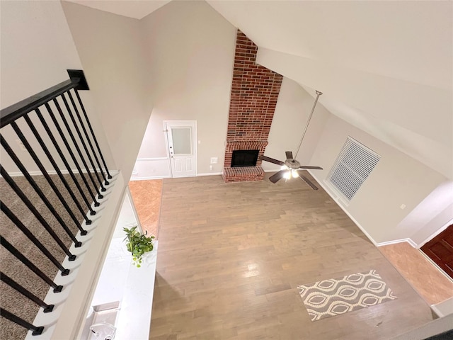 living room featuring ceiling fan, a fireplace, high vaulted ceiling, and wood-type flooring