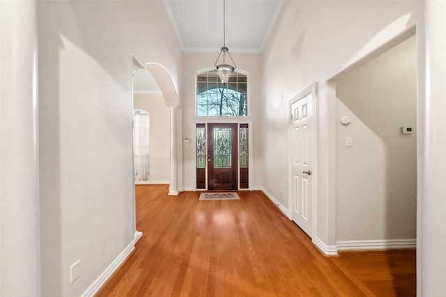 entryway with decorative columns, crown molding, hardwood / wood-style floors, and a high ceiling