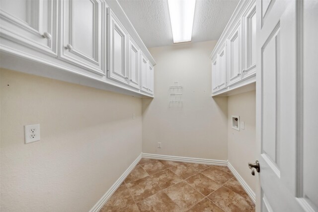 clothes washing area featuring light tile patterned flooring, cabinets, a textured ceiling, and hookup for a washing machine