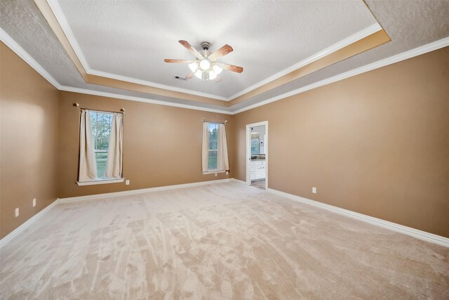 carpeted spare room with a tray ceiling, crown molding, ceiling fan, and a textured ceiling