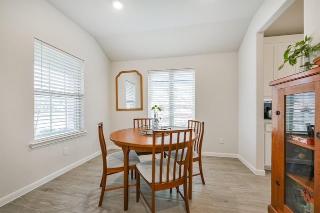 dining space with a wealth of natural light, light hardwood / wood-style floors, and lofted ceiling