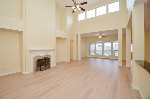 unfurnished living room featuring ceiling fan, light hardwood / wood-style floors, and a high ceiling