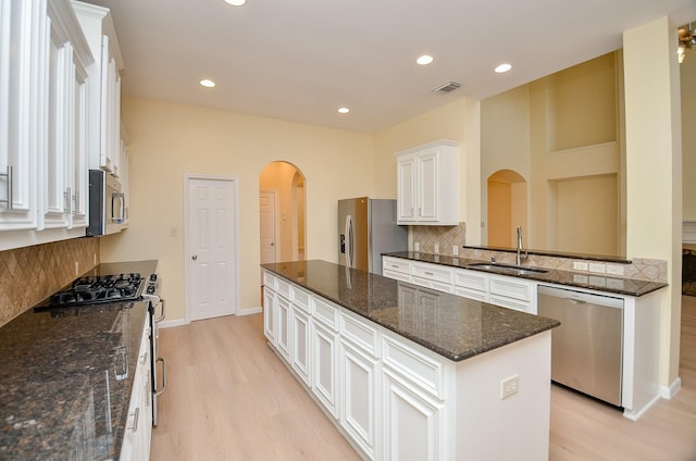 kitchen featuring a center island, sink, dark stone countertops, appliances with stainless steel finishes, and white cabinetry