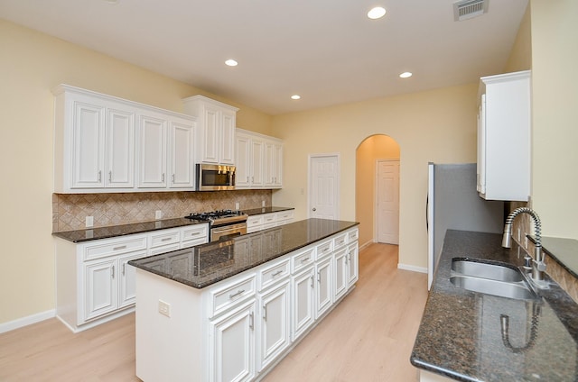 kitchen featuring decorative backsplash, appliances with stainless steel finishes, white cabinetry, and sink