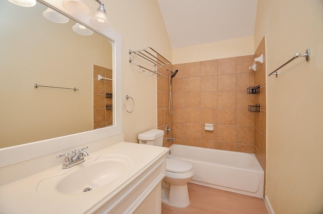 full bathroom featuring vanity, wood-type flooring, tiled shower / bath combo, and toilet