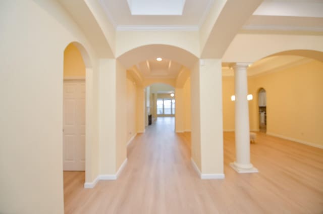 corridor featuring light hardwood / wood-style flooring, crown molding, and ornate columns