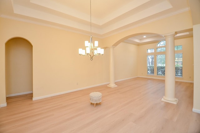 spare room with a tray ceiling, wood-type flooring, and a notable chandelier