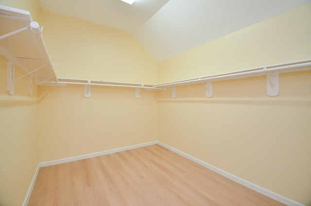 spacious closet featuring hardwood / wood-style floors and vaulted ceiling