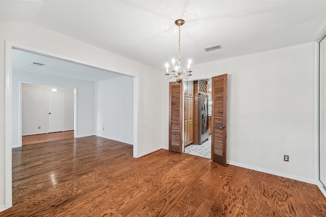 spare room featuring an inviting chandelier and hardwood / wood-style flooring