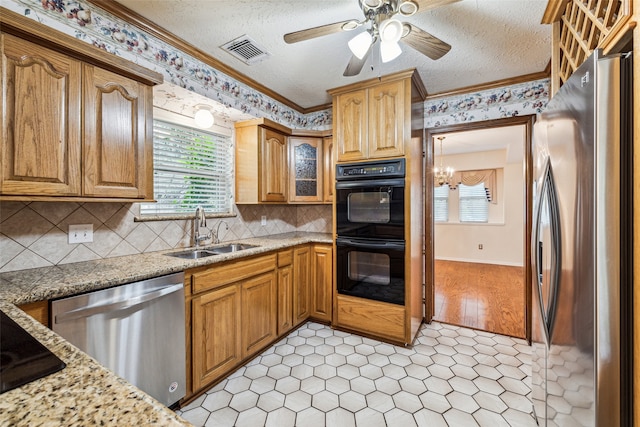 kitchen featuring ceiling fan with notable chandelier, sink, a textured ceiling, appliances with stainless steel finishes, and light stone counters