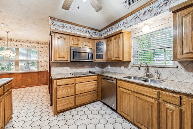 kitchen featuring light stone countertops, a textured ceiling, stainless steel appliances, sink, and decorative light fixtures