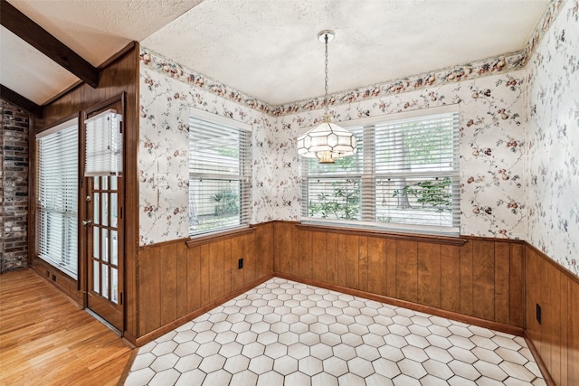 unfurnished dining area with vaulted ceiling with beams, a textured ceiling, and an inviting chandelier