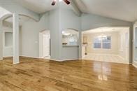 unfurnished living room with ceiling fan and lofted ceiling with beams