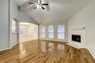 unfurnished living room with ceiling fan, lofted ceiling with beams, and hardwood / wood-style flooring