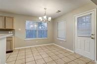 kitchen featuring a wealth of natural light, light tile patterned floors, hanging light fixtures, and an inviting chandelier