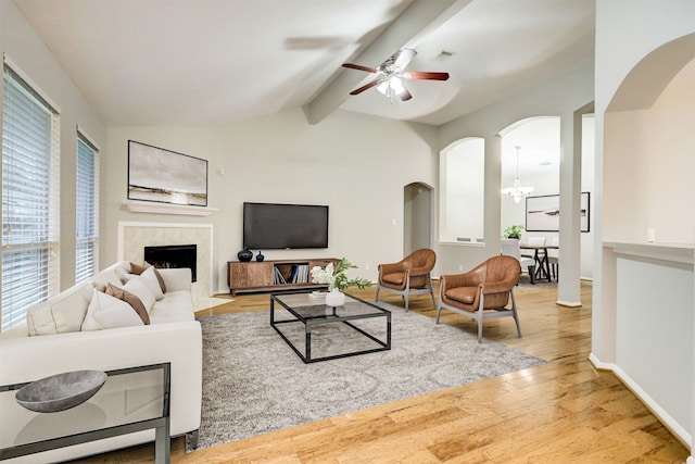 living room with lofted ceiling with beams, light hardwood / wood-style floors, a fireplace, and ceiling fan with notable chandelier