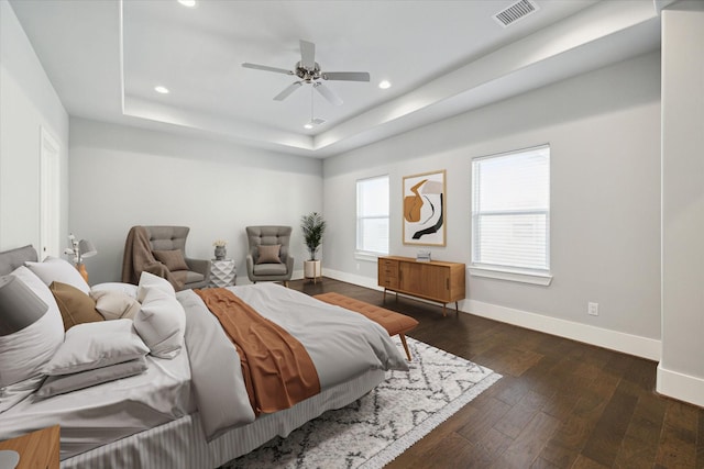 bedroom with ceiling fan, a raised ceiling, and dark wood-type flooring