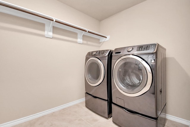 washroom with light tile patterned floors and washer and clothes dryer