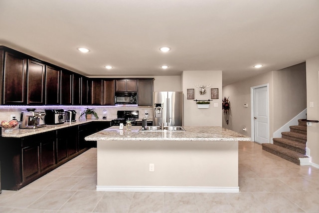 kitchen with a center island with sink, light tile patterned floors, black appliances, and sink