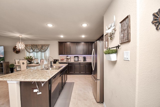 kitchen featuring sink, an island with sink, dark brown cabinets, light tile patterned flooring, and appliances with stainless steel finishes