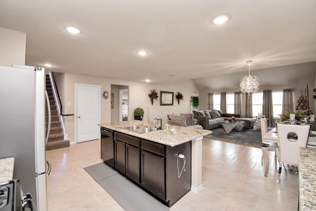 kitchen featuring light stone counters, sink, white refrigerator, a center island with sink, and black dishwasher