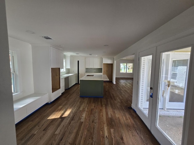 kitchen featuring dark hardwood / wood-style flooring, backsplash, stainless steel dishwasher, white cabinets, and a kitchen island