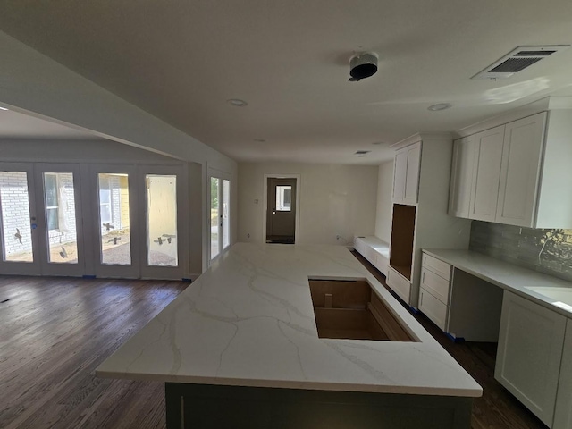 kitchen with light stone countertops, decorative backsplash, a center island, and white cabinetry