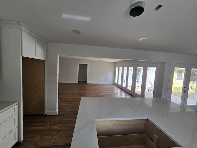 kitchen with white cabinets, french doors, dark hardwood / wood-style floors, and light stone counters