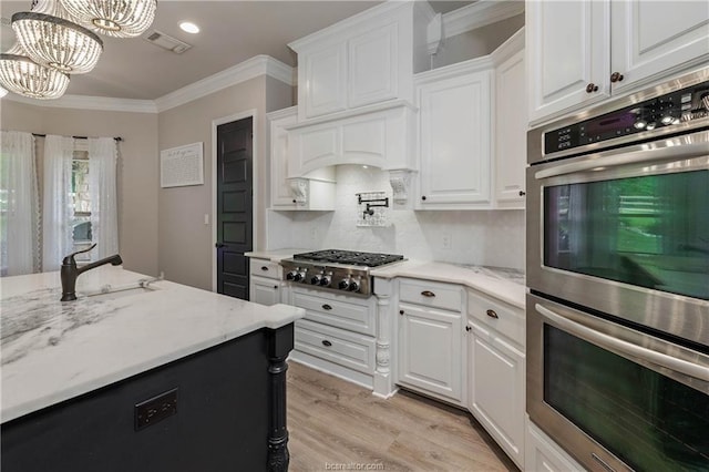 kitchen featuring appliances with stainless steel finishes, tasteful backsplash, pendant lighting, white cabinets, and a chandelier