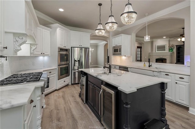 kitchen featuring white cabinetry, a kitchen island with sink, beverage cooler, and stainless steel appliances