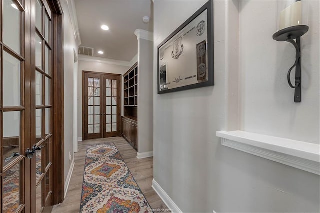 hall with french doors, light hardwood / wood-style flooring, and ornamental molding