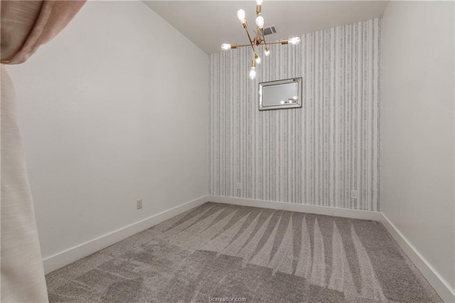 spare room featuring carpet and a chandelier