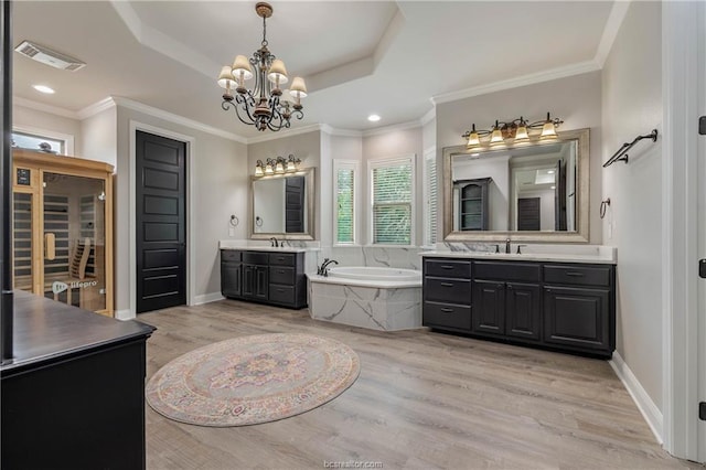 bathroom with vanity, a raised ceiling, a chandelier, hardwood / wood-style floors, and tiled bath