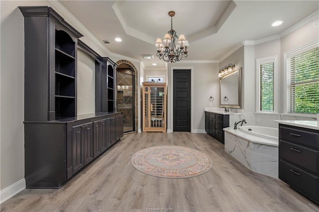 bathroom with hardwood / wood-style floors, vanity, an inviting chandelier, a raised ceiling, and tiled bath