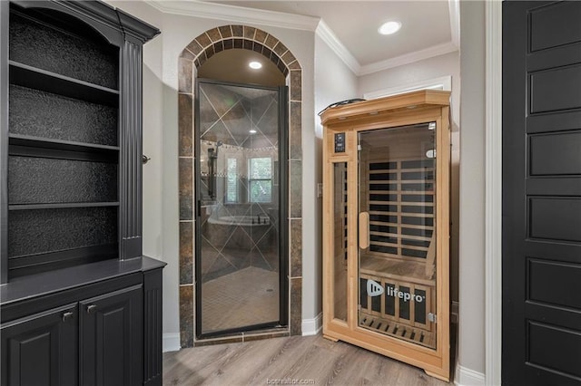 wine cellar with light wood-type flooring, crown molding, and wine cooler