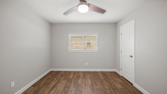 empty room with ceiling fan, dark hardwood / wood-style flooring, and a textured ceiling